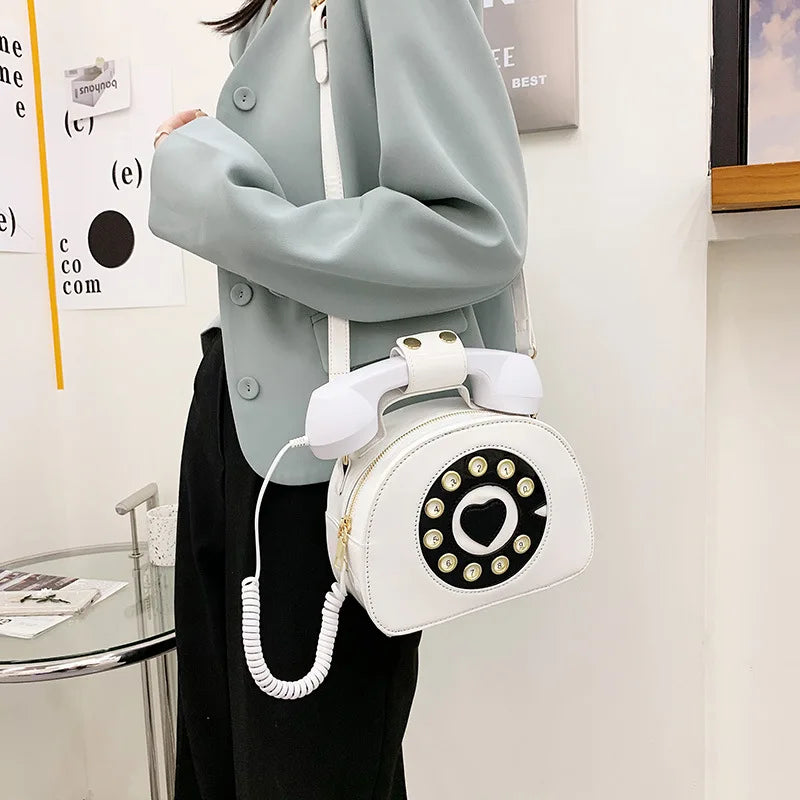 Person holding a white phone-shaped handbag with a retro design.