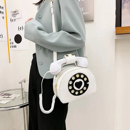 Person holding a white phone-shaped handbag with a retro design.