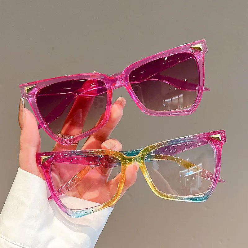 Hand holding two pairs of colourful sunglasses against a neutral background