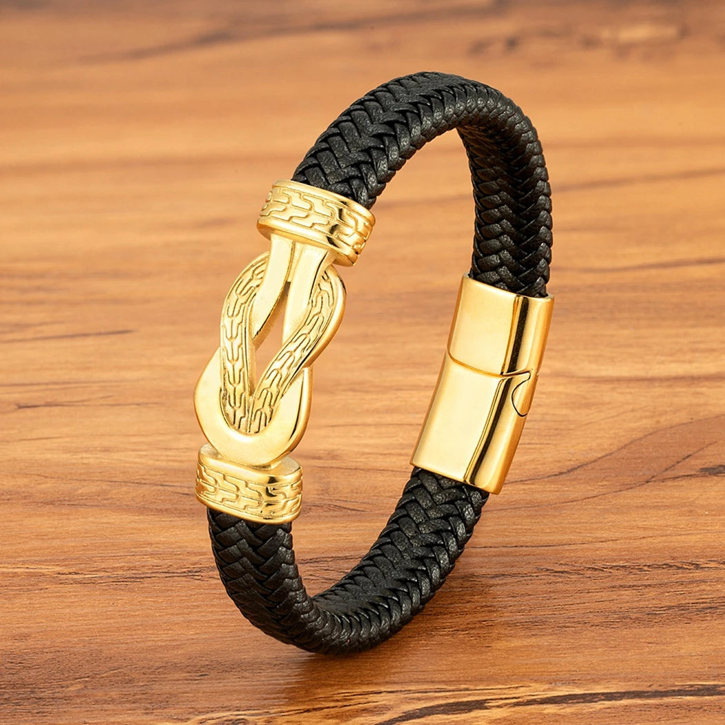 Black braided leather bracelet with gold clasp on a wooden surface