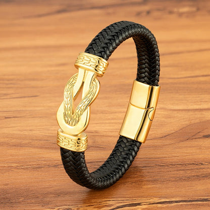Black braided leather bracelet with gold clasp on a wooden surface