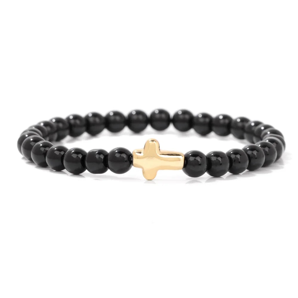 Black beaded bracelet with a gold cross charm on a white background