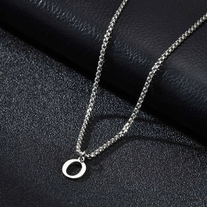 Silver necklace with a 'O' pendant on a black textured surface