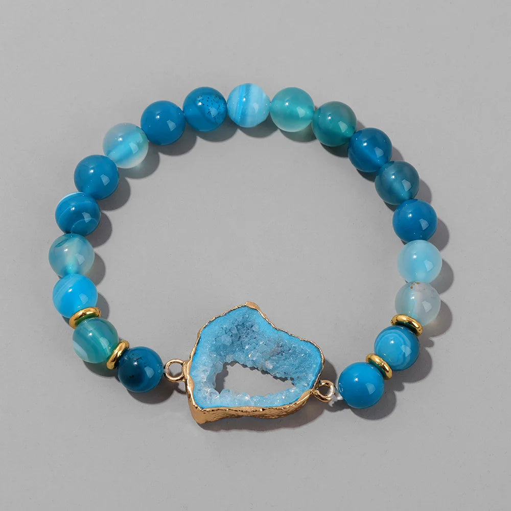 Blue beaded bracelet with a central blue stone on a grey background