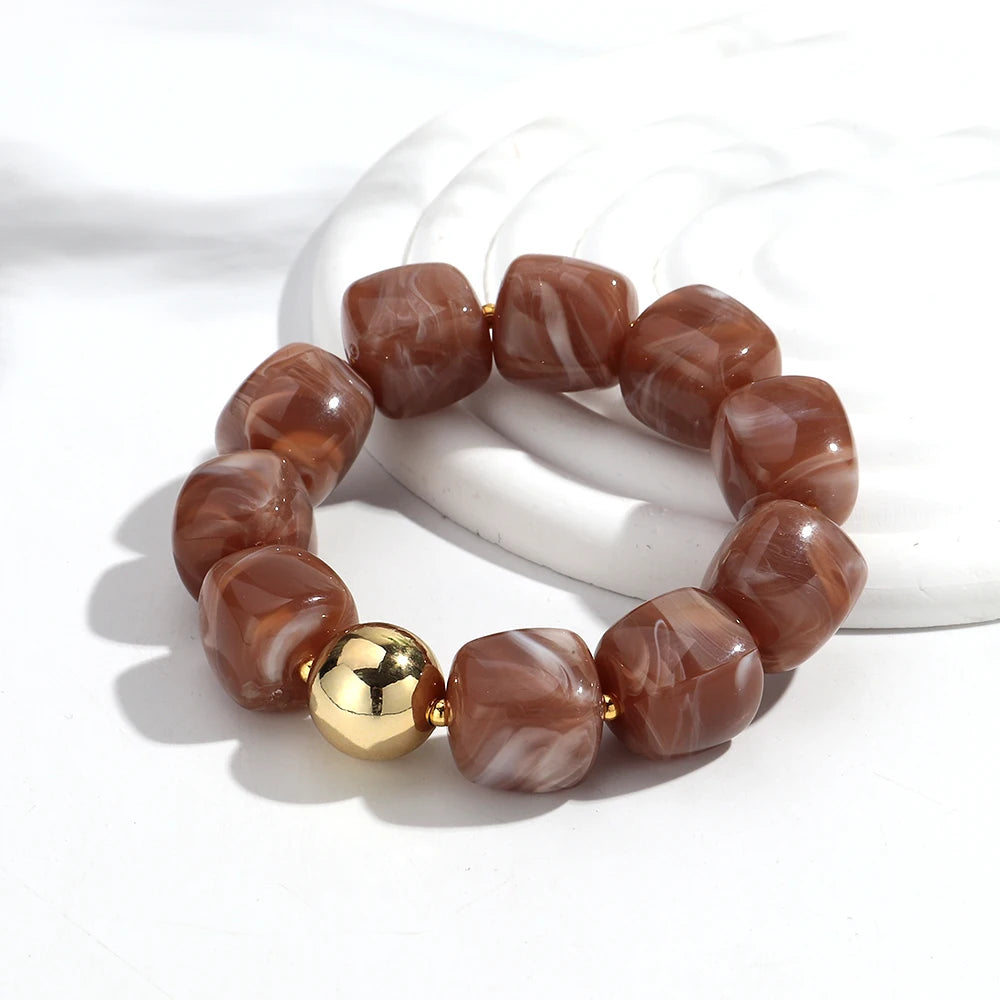 Bracelet with brown marbled beads and a gold accent on a white background