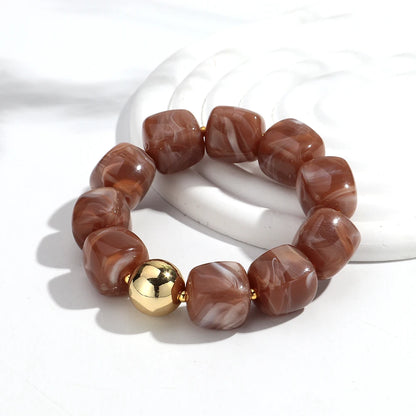 Bracelet with brown marbled beads and a gold accent on a white background