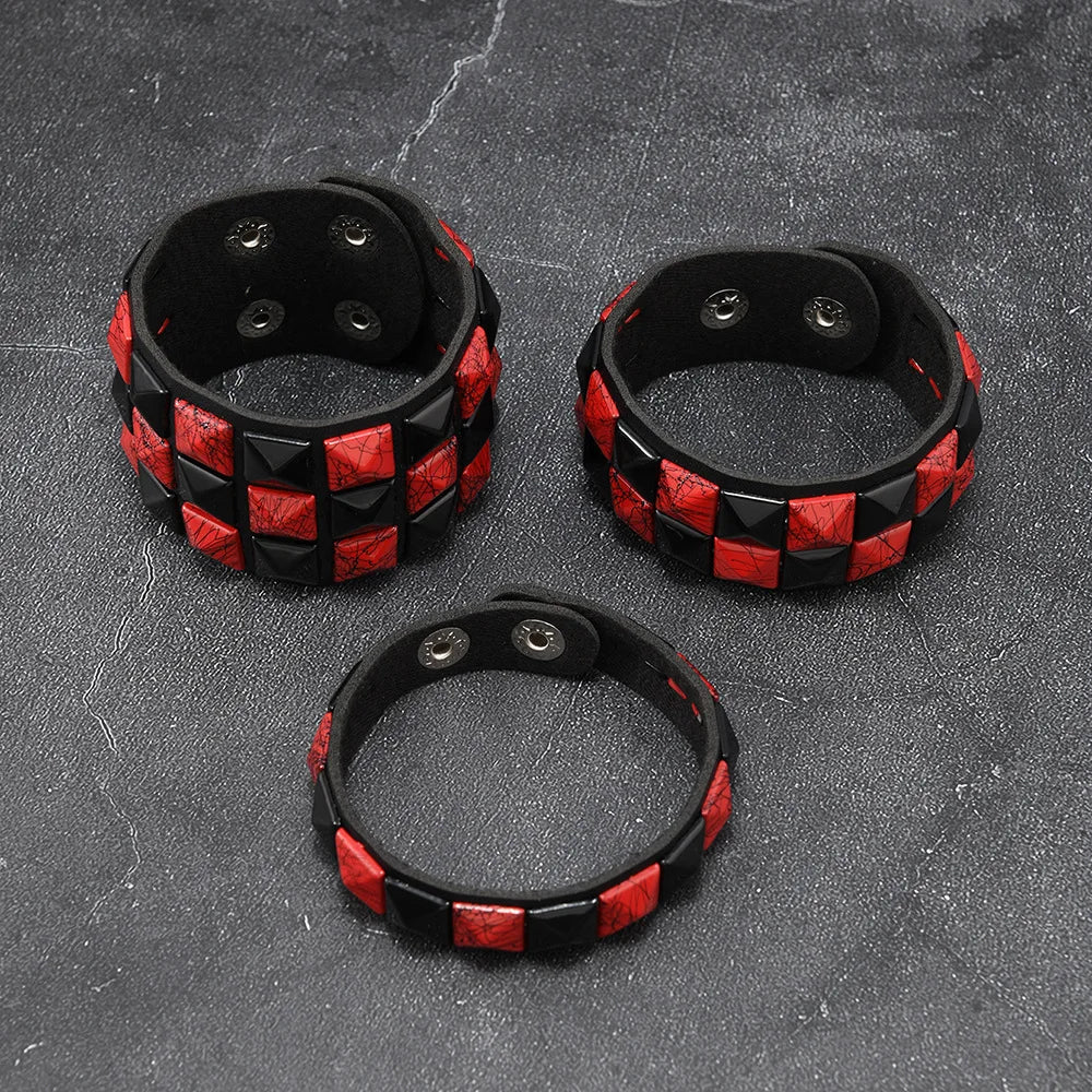 Three black and red checkered leather cuffs on a textured grey surface
