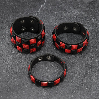 Three black and red checkered leather cuffs on a textured grey surface