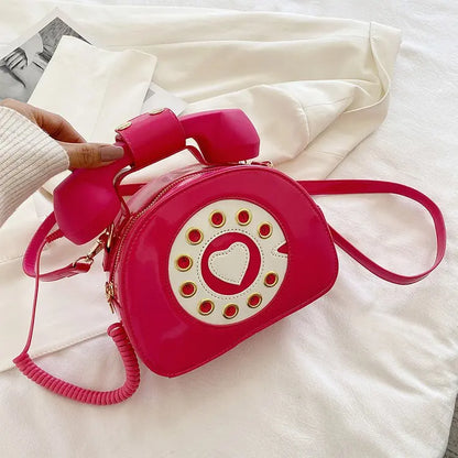 Pink phone-shaped handbag with a heart design on a white fabric background
