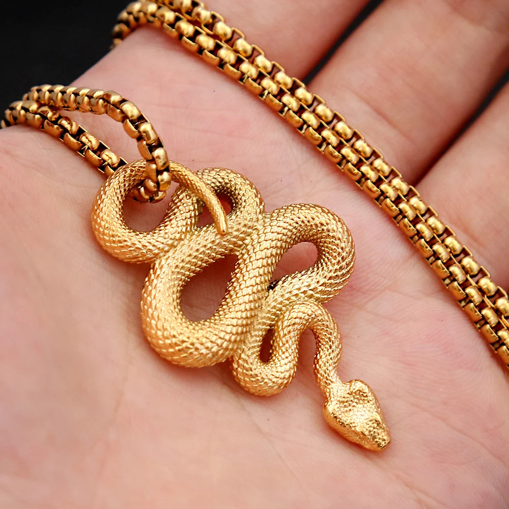 Gold snake pendant on a chain held in a hand