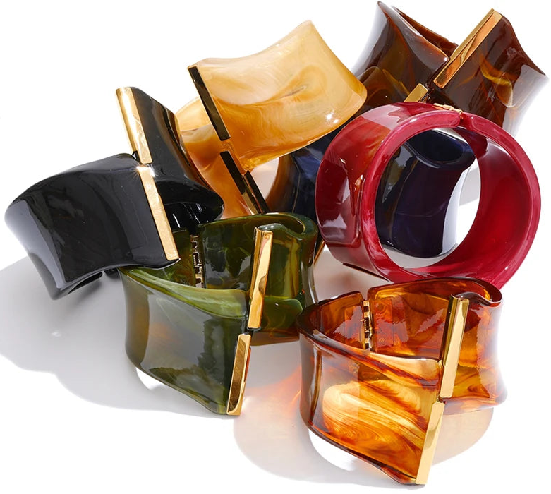 Colourful resin bracelets with gold accents on a white background