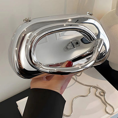Silver handbag held by a person against a neutral background