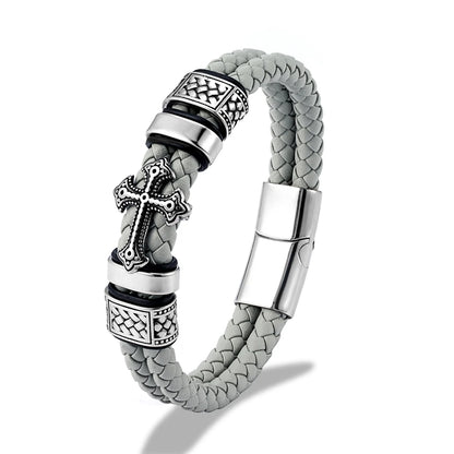 A silver-toned braided leather bracelet with a central cross charm, textured metal spacer beads, and a polished magnetic clasp, shown on a white background.