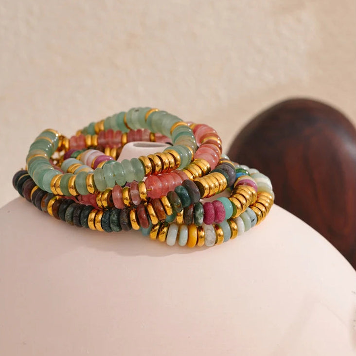 Set of colourful beaded bracelets on a beige surface.