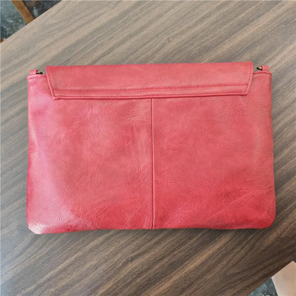 Red leather clutch bag on a wooden surface