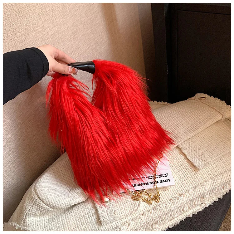 Red fluffy handbag held by a hand on a beige surface