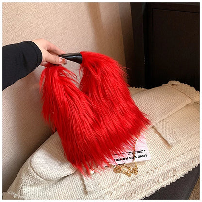 Red fluffy handbag held by a hand on a beige surface
