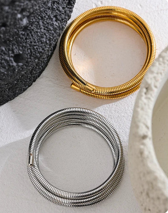 Gold and silver bracelets on a textured surface.
