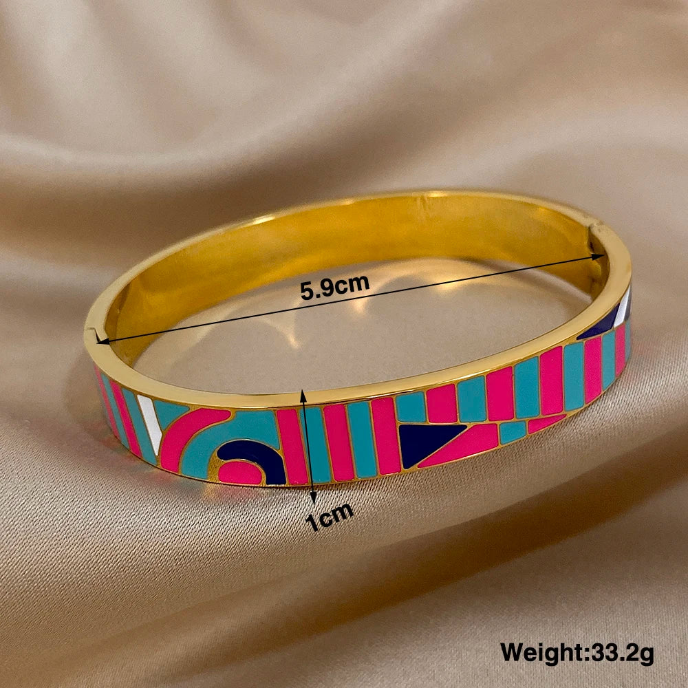 Gold bangle with colourful pattern and measurements on a beige fabric background