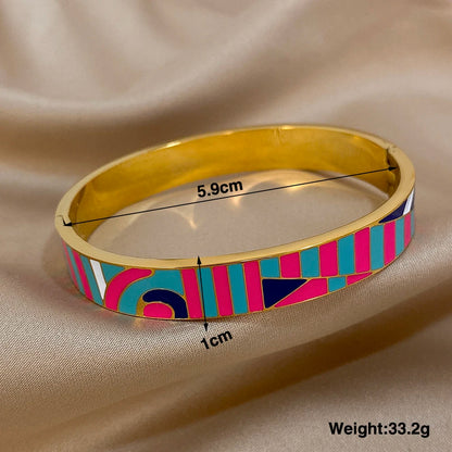 Gold bangle with colourful pattern and measurements on a beige fabric background