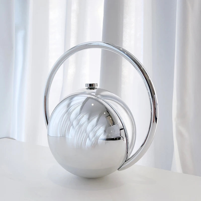 Silver spherical object with a reflective surface on a white background