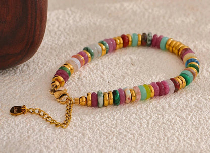 Colourful beaded bracelets on a textured surface with a wooden bowl.