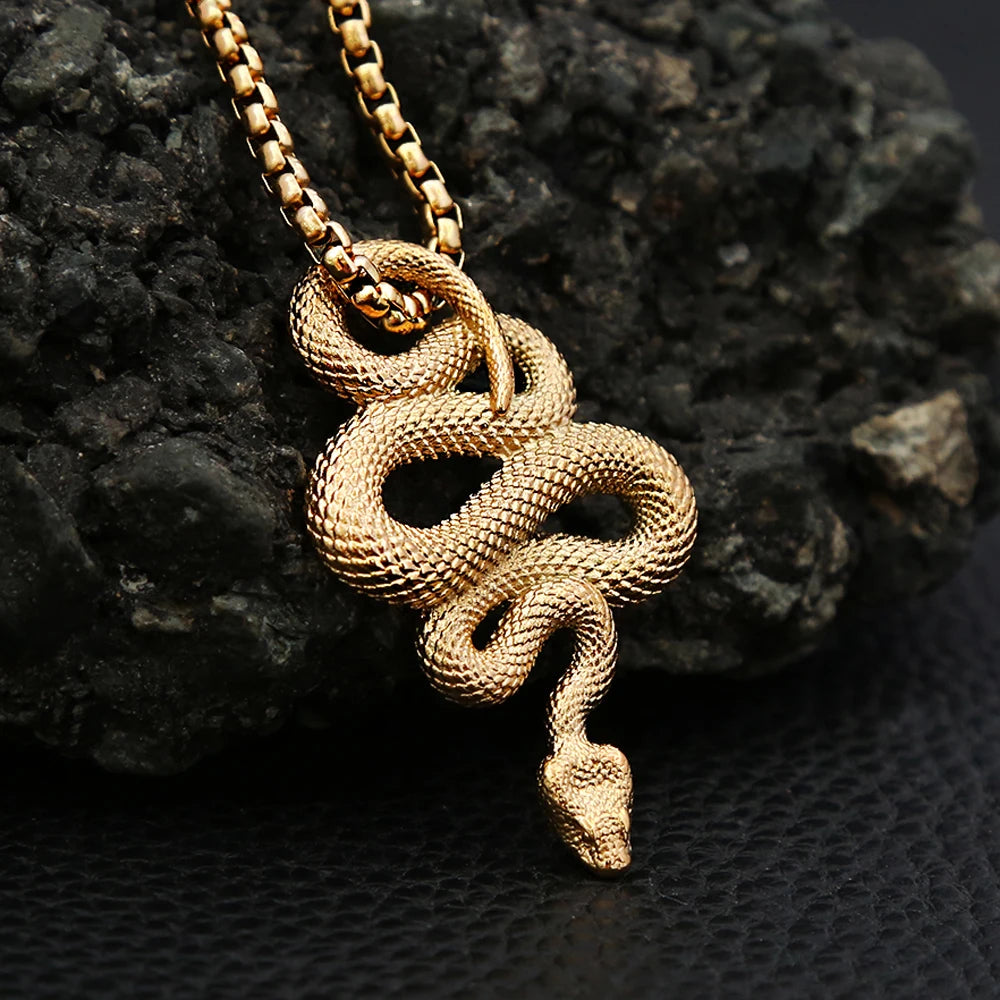 Gold snake pendant necklace on a dark textured surface