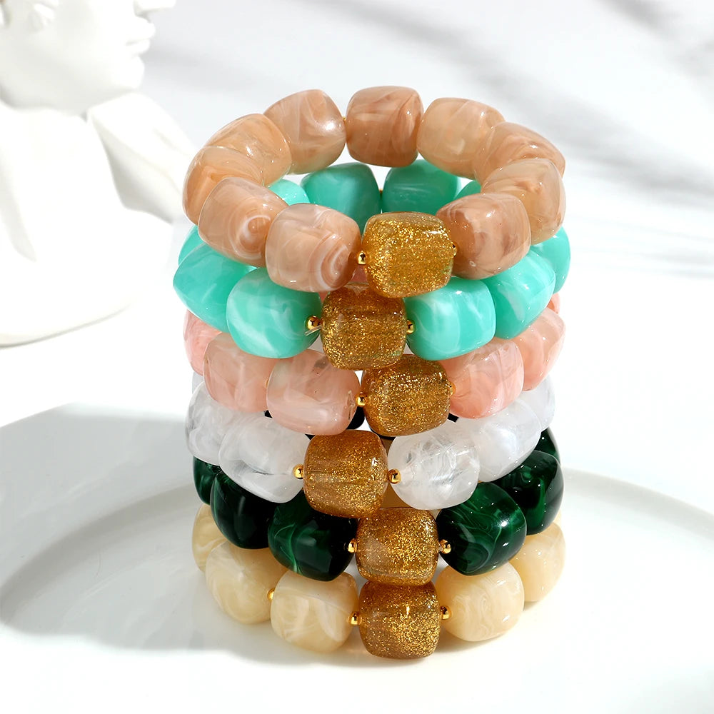 Stack of colourful beaded bracelets on a white surface