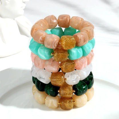 Stack of colourful beaded bracelets on a white surface