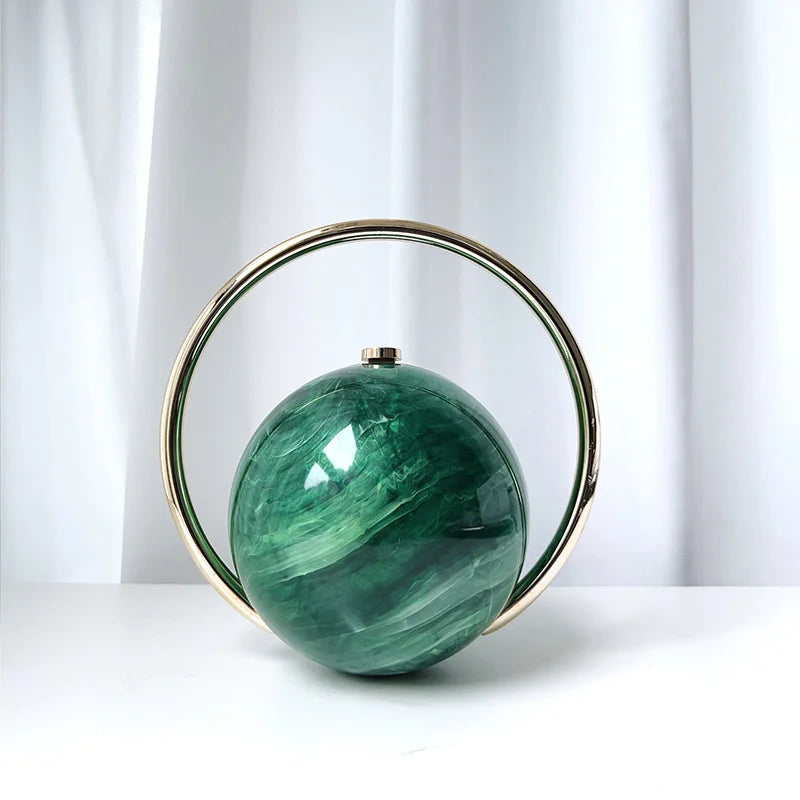 Green spherical clutch bag with gold rim on a white background