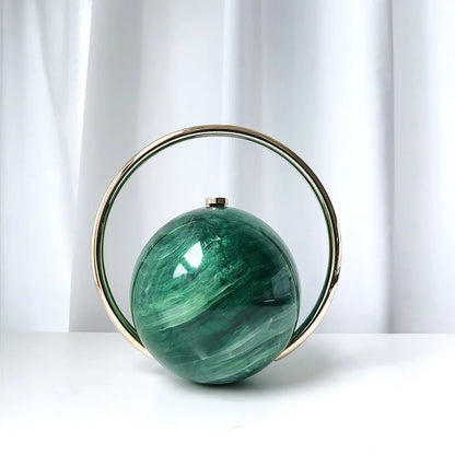 Green spherical clutch bag with gold rim on a white background