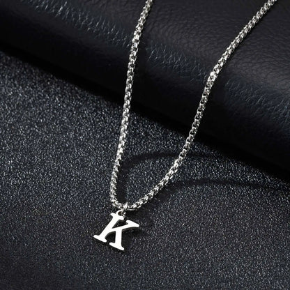Silver necklace with a 'K' pendant on a dark textured surface