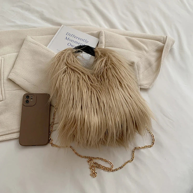 Beige fluffy handbag with a gold chain on a white surface