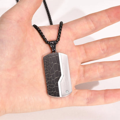 Dog tag pendant with black textured design on a hand