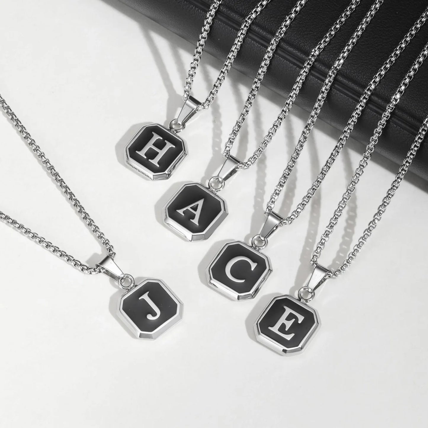 Silver necklaces with letter pendants on a white background