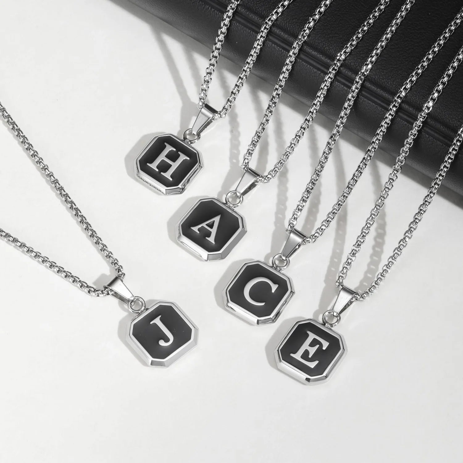 Silver necklaces with letter pendants on a white background