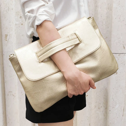 Gold clutch bag held by a person against a neutral background