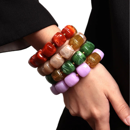 Colourful beaded bracelets on a person's wrist against a white background