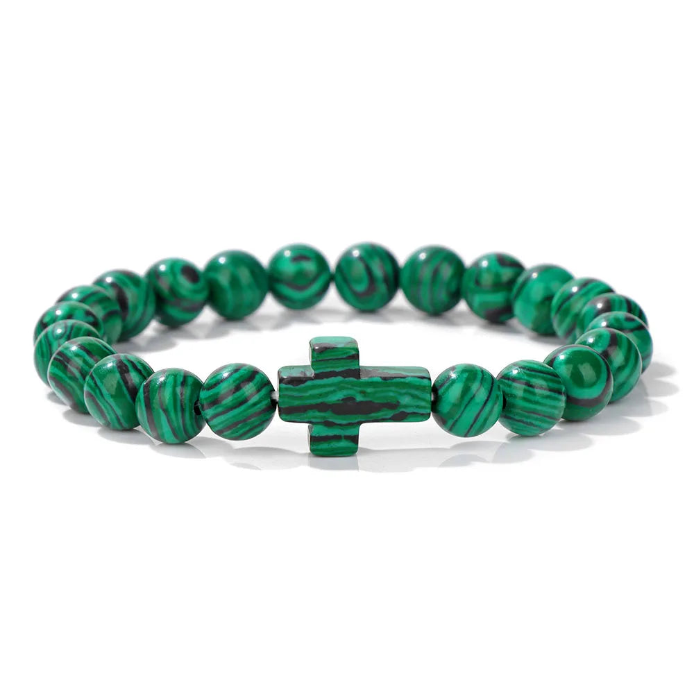 Green beaded bracelet with a cross charm on a white background