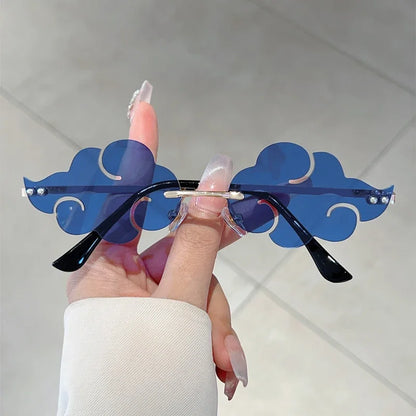 Sunglasses with blue cloud-shaped frames held by a hand against a light background