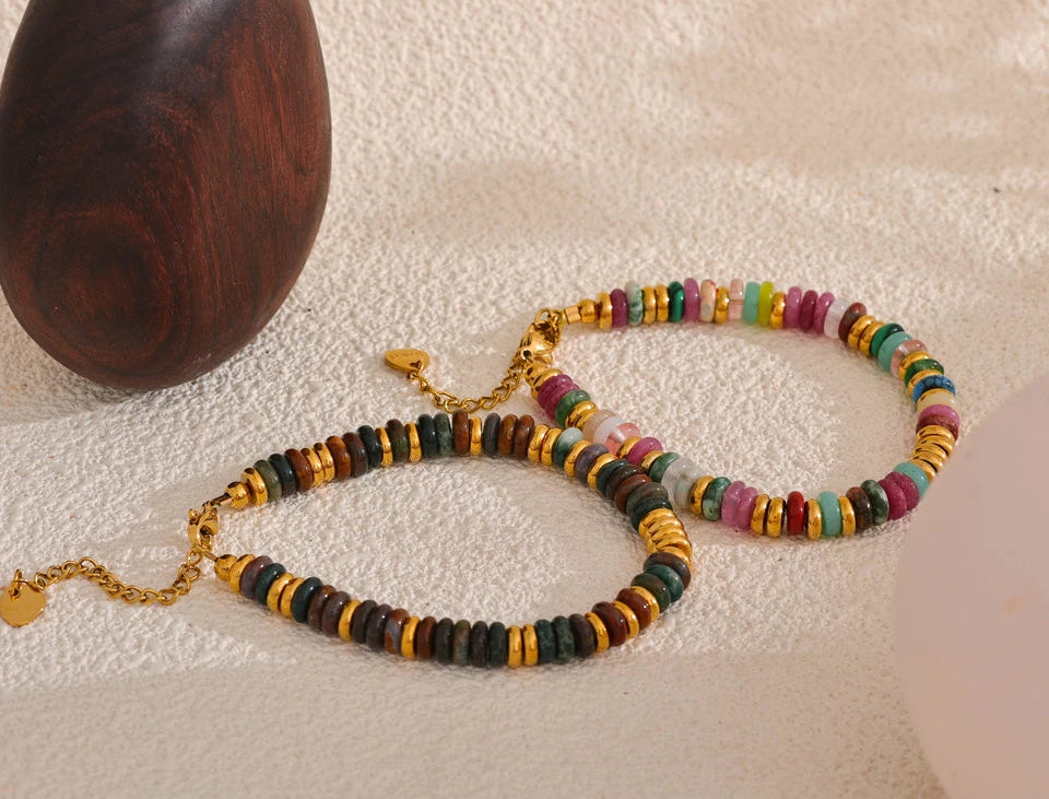 Colourful beaded necklace and bracelet on a textured surface