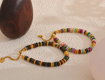 Colourful beaded necklace and bracelet on a textured surface