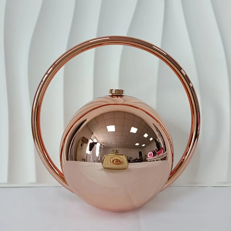 Rose gold circular clutch bag on a white background