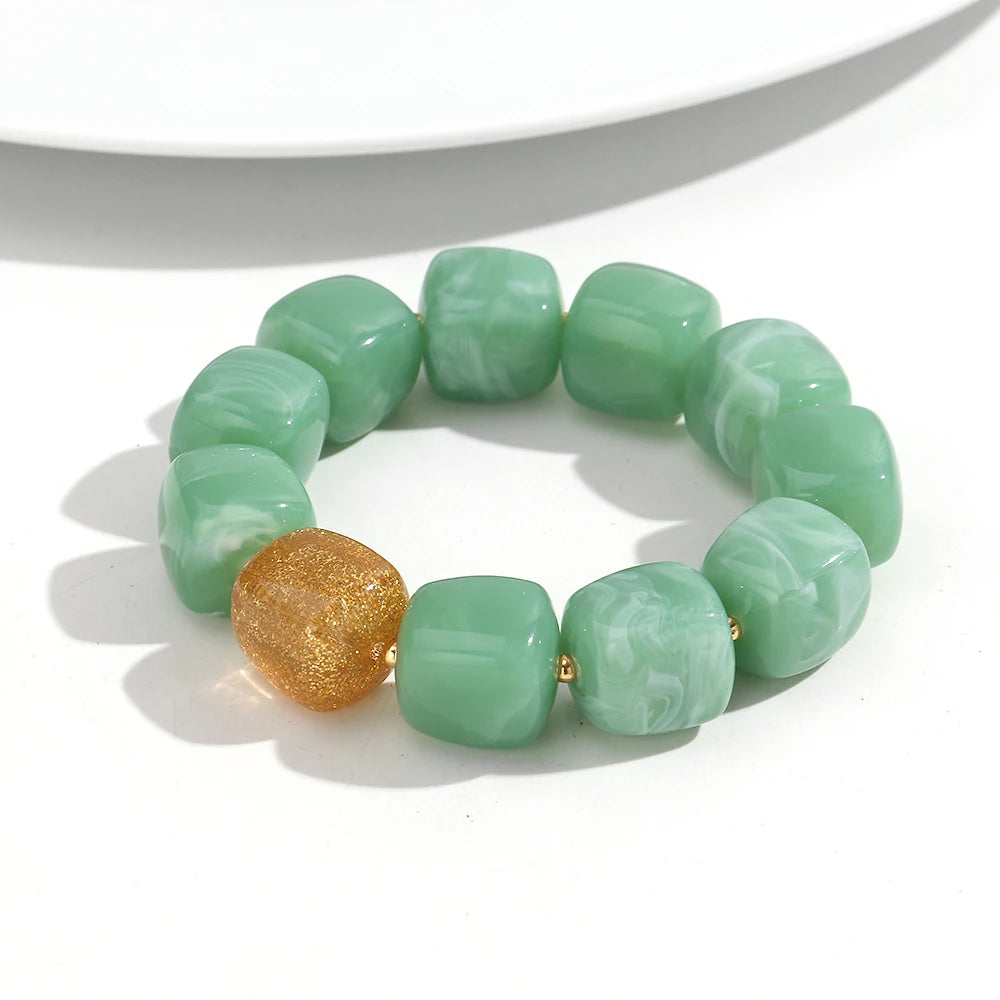Green beaded bracelet with a gold accent on a white background