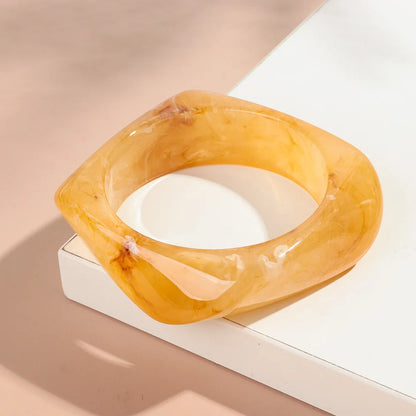 Orange bangle on a white surface with a beige background