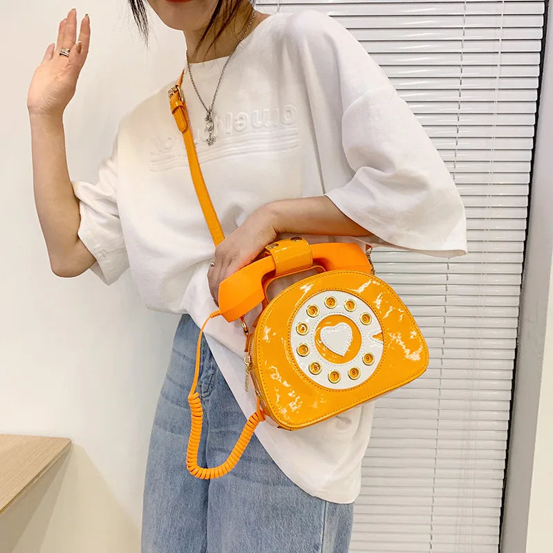 Person holding an orange phone-shaped bag with a white background