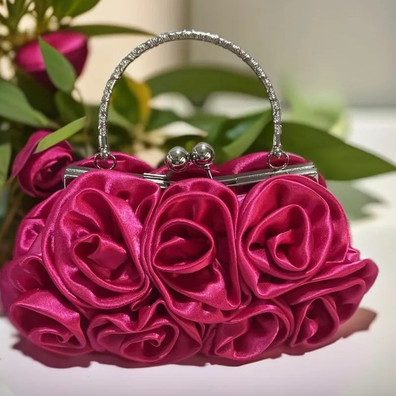 Pink rose handbag with silver handle against a blurred green leafy background