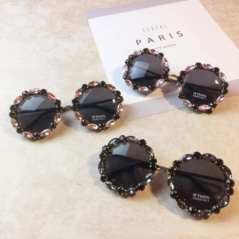 Round sunglasses with decorative frames on a textured surface