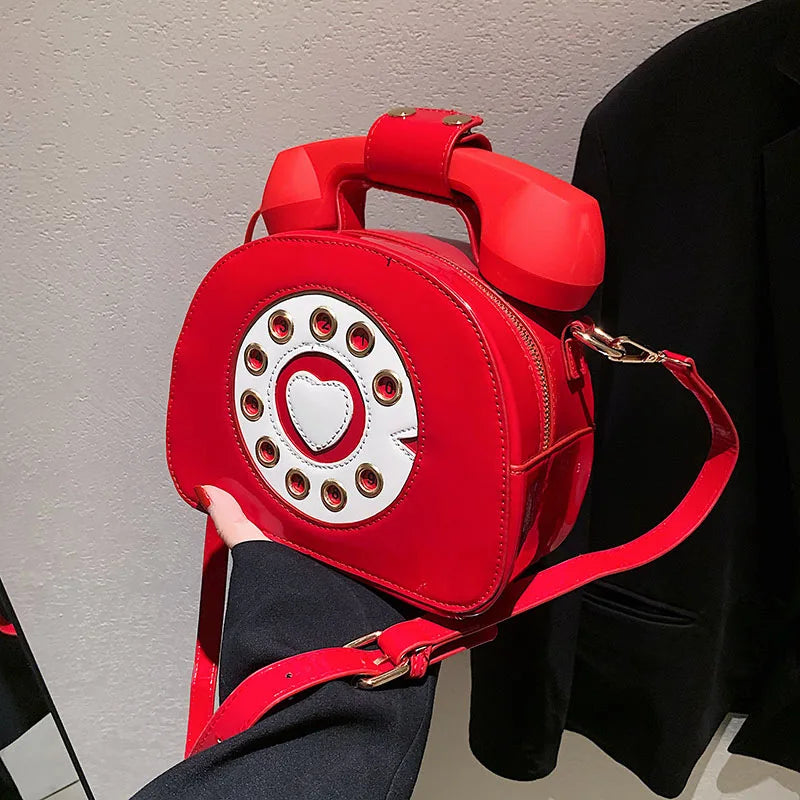 Red phone-shaped handbag with a heart design on a neutral background