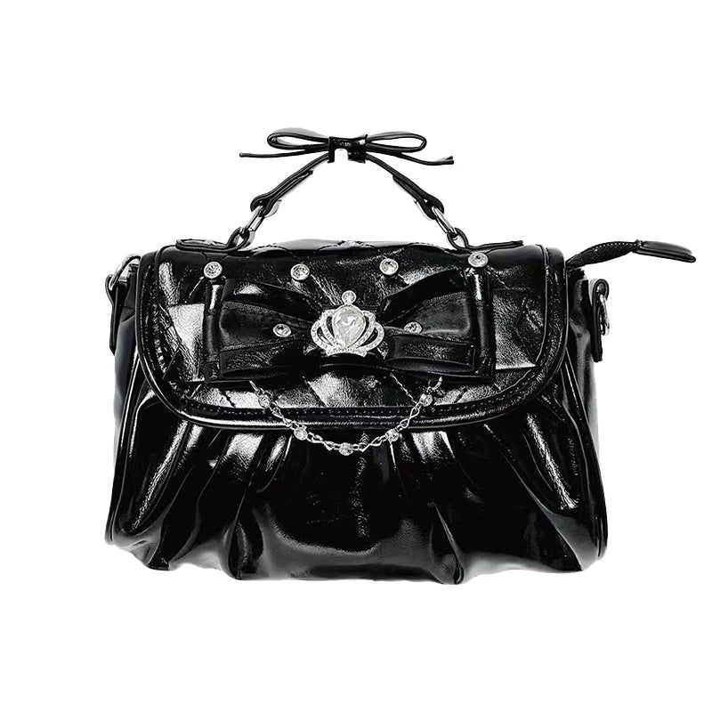 Black handbag with decorative bow and chain on a white background